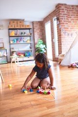 Beautiful toddler girl sitting on the floor playing with train at kindergarten