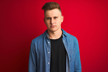Obraz premium Young handsome man wearing denim shirt standing over isolated red background skeptic and nervous, frowning upset because of problem. Negative person.
