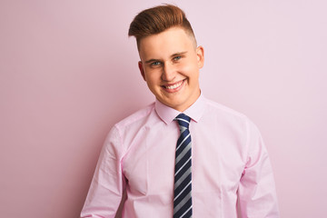 Young handsome businessman wearing shirt and tie standing over isolated pink background with hands together and crossed fingers smiling relaxed and cheerful. Success and optimistic
