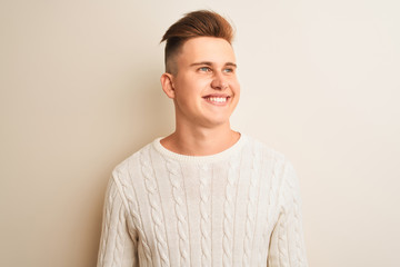 Young handsome man wearing winter sweater standing over isolated white background looking away to...