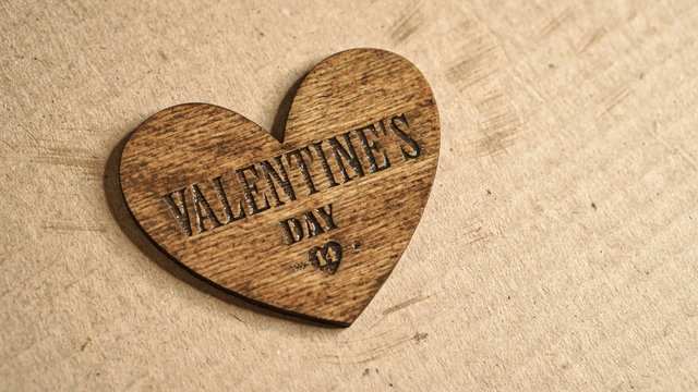 Laser cut wooden 3d symbol of valentine's day on hand render on a sheet of cardboard. Plywood heart