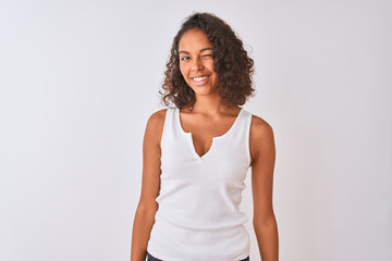 Young brazilian woman wearing casual t-shirt standing over isolated white background winking...