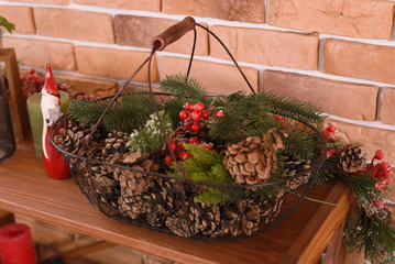 basket with cones and branches of a Christmas tree, against a brick wall, greeting card