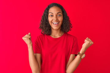 Young brazilian woman wearing t-shirt standing over isolated red background screaming proud and celebrating victory and success very excited, cheering emotion