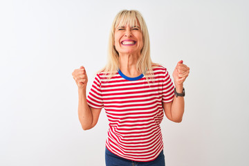 Fototapeta na wymiar Middle age woman wearing casual striped t-shirt standing over isolated white background very happy and excited doing winner gesture with arms raised, smiling and screaming for success. Celebration