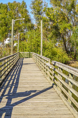 A fishing pier over water in a park on a sunny day.