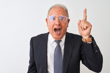 Senior grey-haired businessman wearing suit and glasses over isolated white background pointing finger up with successful idea. Exited and happy. Number one.