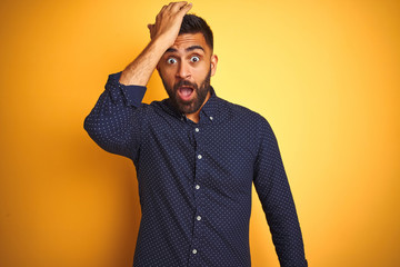 Young handsome indian businessman wearing shirt over isolated yellow background surprised with hand...