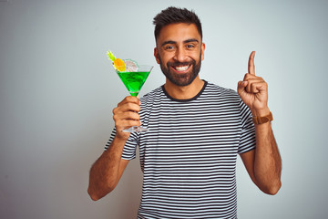 Young indian man drinking cocktail with alcohol standing over isolated white background surprised with an idea or question pointing finger with happy face, number one