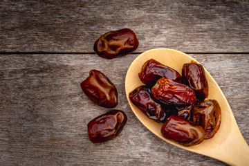 Closeup date palm fruits in wooden spoon isolated on old wood table background. Top view.