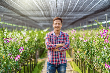 Portrait asian small business owner of orchid gardening farm, The purple orchids are blooming in the garden farm, Happiness founder are arms crossed, Purple orchids in farming of bangkok, thailand.