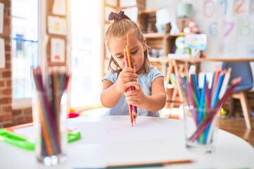 Young beautiful blonde girl kid enjoying play school with toys at kindergarten, smiling happy painting with pencil colors at home