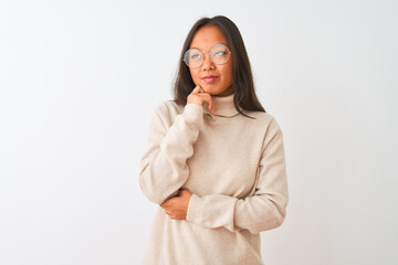 Young chinese woman wearing turtleneck sweater and glasses over isolated white background with hand on chin thinking about question, pensive expression. Smiling with thoughtful face. Doubt concept.