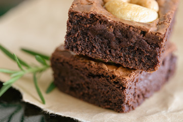 Homemade bakery dark chocolate fudge brownies cake topping cashew nut stacked on brown paper in closeup view to show texture. Delicious bitter sweet and chewy. Brownie is one type of chocolate cake.