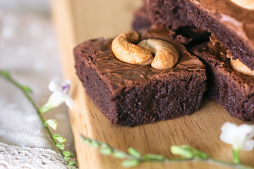 Fresh baked dark chocolate fudge brownies topping with cashew nut stacked on wood plate. Delicious...