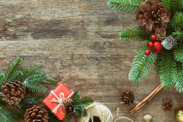 Christmas plank background decoration pine leaves and cones, gift box and holly balls on wood table with copy space in top view flat lay. Vintage wooden Christmas wallpaper for xmas celebration.