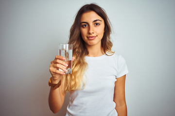Young beautiful woman drinking a glass of water over white isolated background with a confident expression on smart face thinking serious