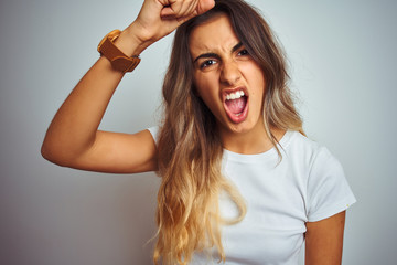 Young beautiful woman wearing t-shirt over white isolated background annoyed and frustrated shouting with anger, crazy and yelling with raised hand, anger concept