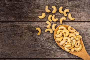 Cashew nut in wooden spoon isolated  on old wood table background. Top view  Space for text.
