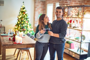 Young beautiful couple smiling happy and confident. Toasting with cup of wine celebrating christmas at home