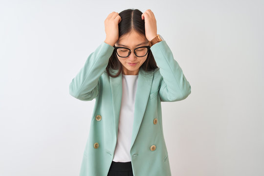 Chinese businesswoman wearing elegant jacket and glasses over isolated white background suffering from headache desperate and stressed because pain and migraine. Hands on head.