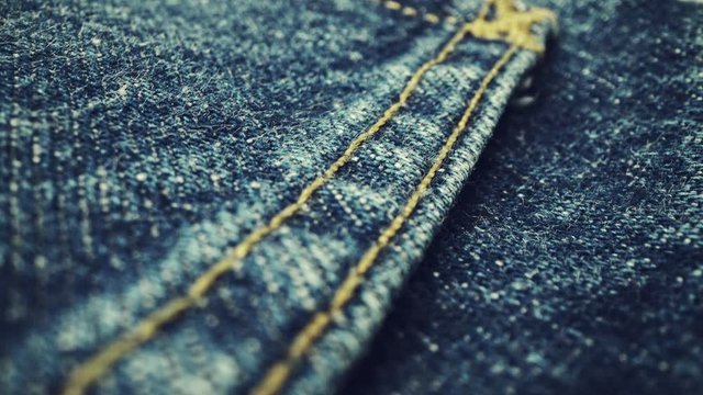 Extreme detailed of blue denim jeans cloth texture in macro dolly shot over the cloth surface. Flow view of clothing material. Textile abstract background. Vintage fashion apparel industry concept.
