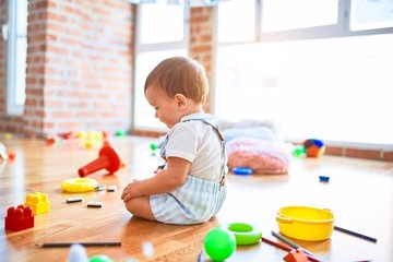 Adorable toddler playing around lots of toys at kindergarten