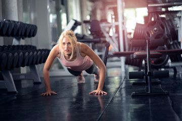 Fototapeta na wymiar Strong woman doing push ups in the gym