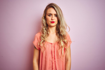 Young beautiful woman wearing t-shirt standing over pink isolated background skeptic and nervous,...