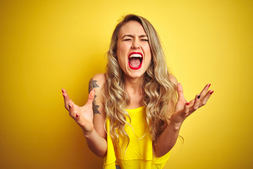 Young attactive woman wearing t-shirt standing over yellow isolated background celebrating mad and...