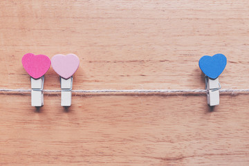 two wooden cloth clips with pink heart sign as a lesbian symbol make a wooden cloth clip with blue heart sign as a man symbol is broken heart. lgbt symbol concept with vintage tone style photo.