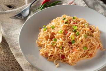 The noodles are in a round white plate placed on a wooden table.noodle concept with copy space