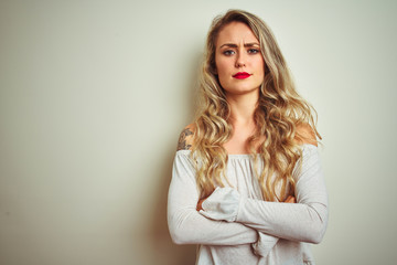 Young beautiful woman standing over white isolated background skeptic and nervous, disapproving expression on face with crossed arms. Negative person.