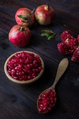 three pomegranate with bowl and wooden spoon on real wooden table