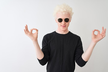 Young albino man wearing black t-shirt and sunglasess standing over isolated white background relax...