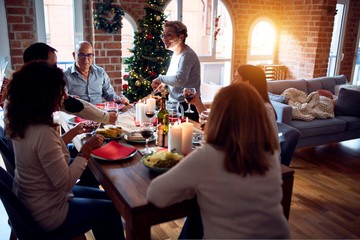 Family and friends dining at home celebrating christmas eve with traditional food and decoration, preparing turkey for dinner