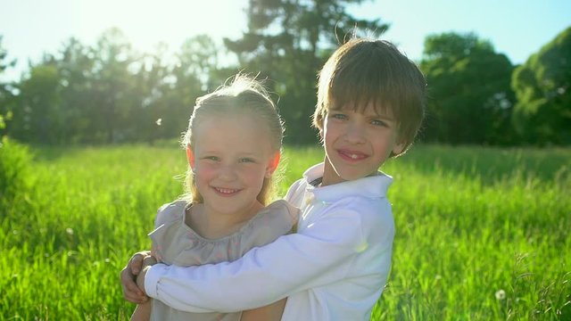 Little cute boy and pretty girl hugging and kissing each other on summer day. Brother and little sister cuddling. Happy family outdoors. children having fun at sunset. childhood first love, friendship