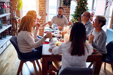 Family and friends dining at home celebrating christmas eve with traditional food and decoration, praying and blessing the table