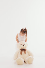 a small child with toy Taddy bear. Girl playing on white background. Concept of gift, childhood