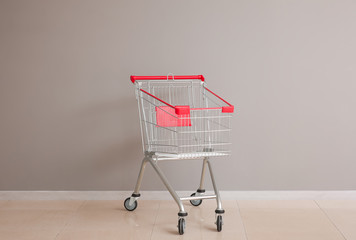 Empty shopping cart near grey wall