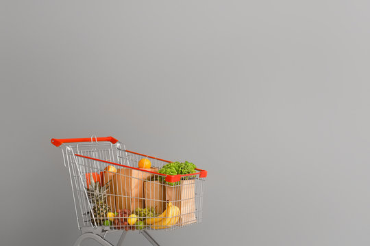 Shopping cart with products near grey wall