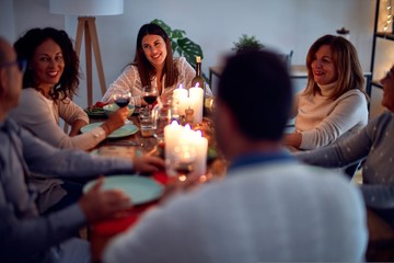Family and friends dining at home celebrating christmas eve with traditional food and decoration, all sitting on the table together