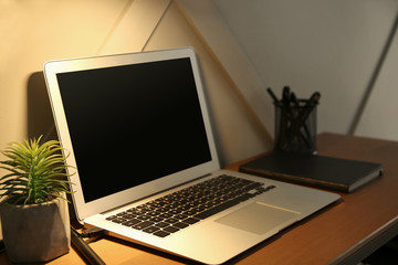 Fototapeta premium Comfortable workplace with modern laptop in evening