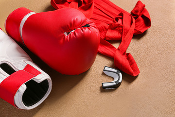 Boxing gloves, wrist bands and mouth piece on color background
