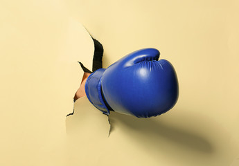 Hand in boxing glove tearing color paper