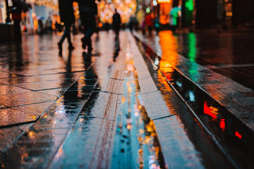 Rainy night in a big city, reflections of lights on the wet road surface.