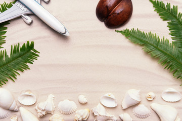 Fototapeta na wymiar Summer vacation flat lay on tropical sandy ocean beach. Holidays concept with airplane, shells, palm leaves - summertime lifestyle, top view arrangement