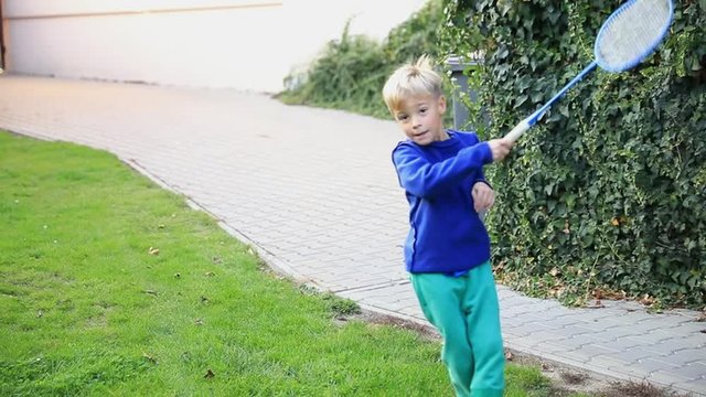 Little boy playing badminton. Racquet sports outdoors. Stabilized video. Slow motion.