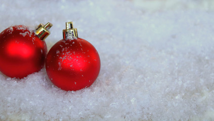 zwei rote christbaumkugeln im schnee