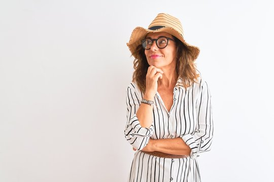 Middle age businesswoman wearing striped dress glasses hat over isolated white background serious face thinking about question, very confused idea